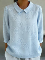 Camicia romantica con colletto Peter Pan e ricami floreali.