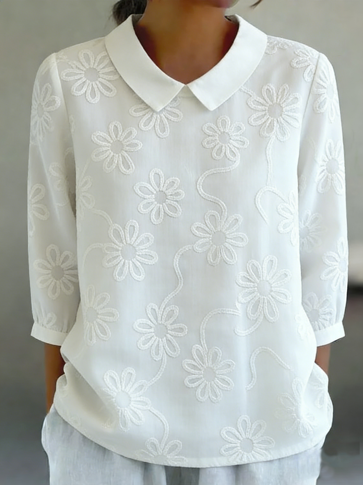 Camicia romantica con colletto Peter Pan e ricami floreali.