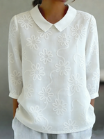 Camicia romantica con colletto Peter Pan e ricami floreali.