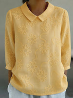 Camicia romantica con colletto Peter Pan e ricami floreali.