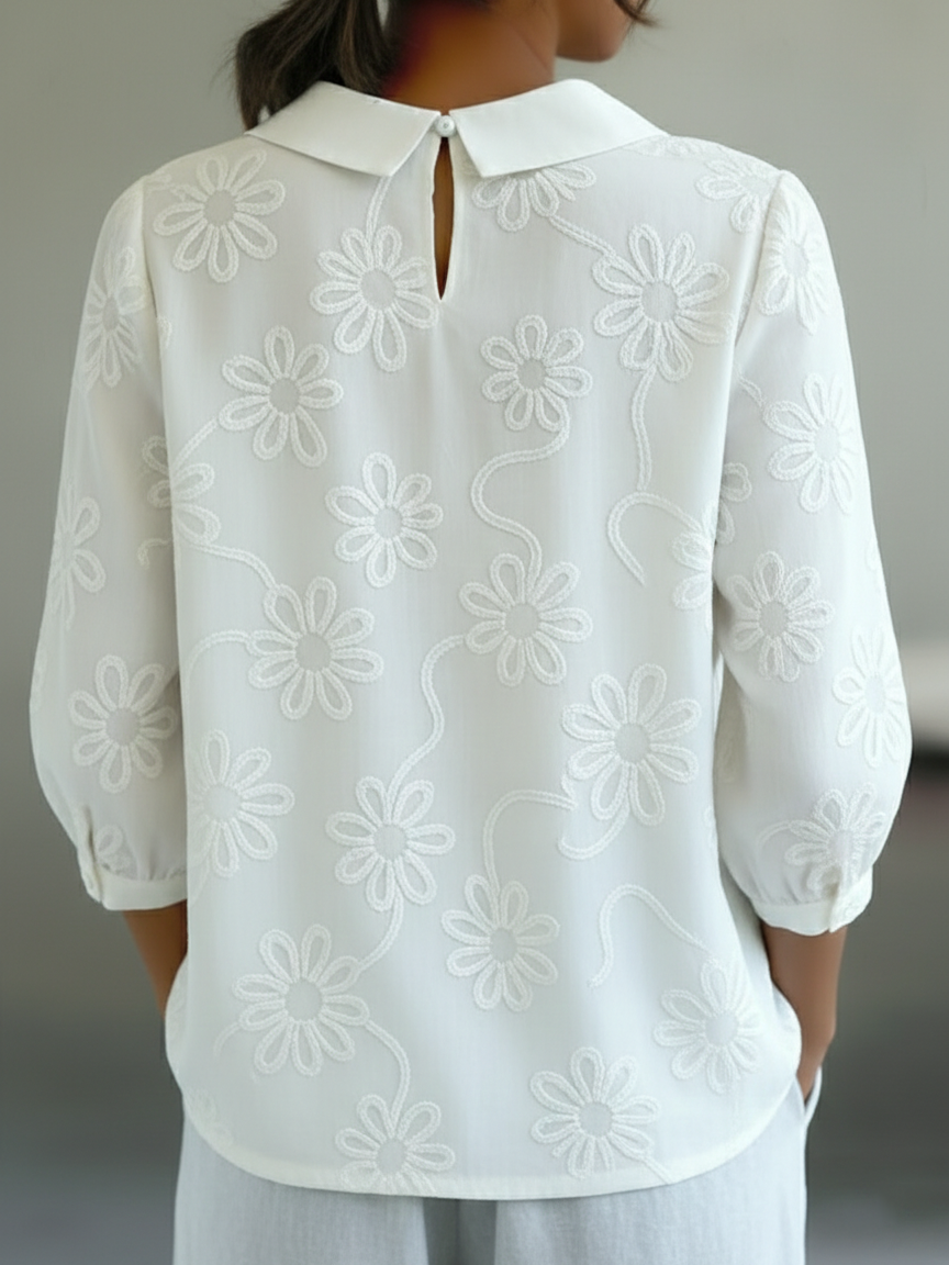 Camicia romantica con colletto Peter Pan e ricami floreali.