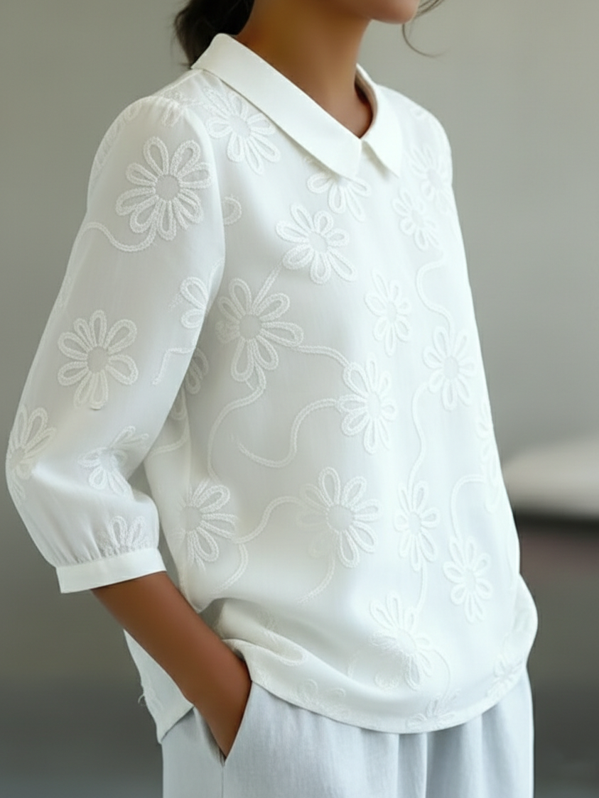 Camicia romantica con colletto Peter Pan e ricami floreali.